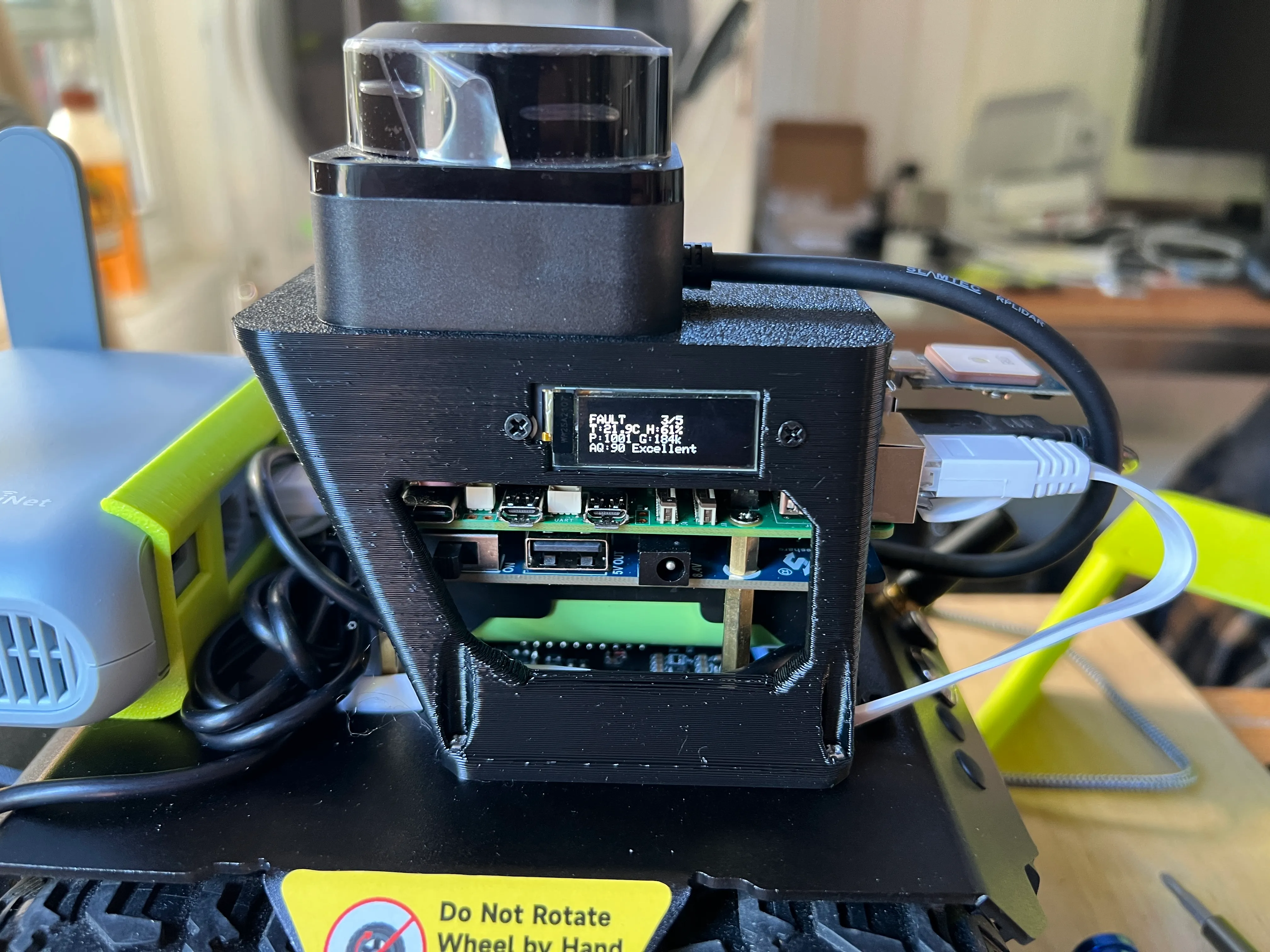 The rover's compute stack on the bench - Raspberry Pi, LiDAR dome, and an OLED showing live telemetry